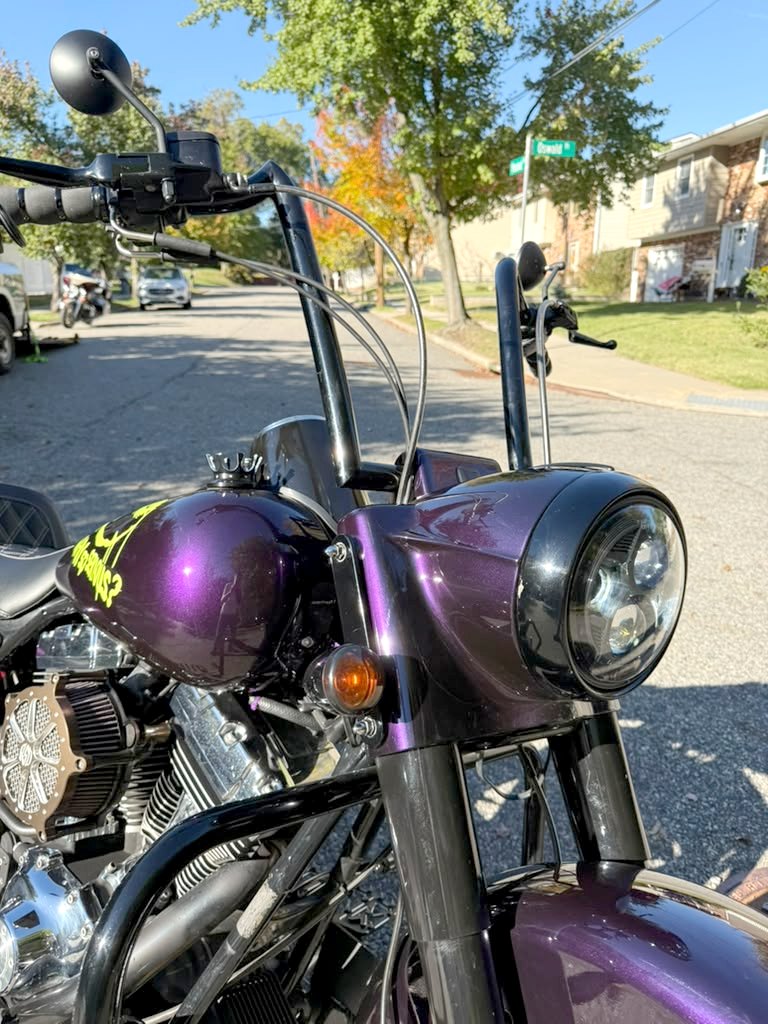 Paars gespoten koplamp, zwarte voorvork en 21 inch fat spoke voorwiel op de Road King Custom 2004